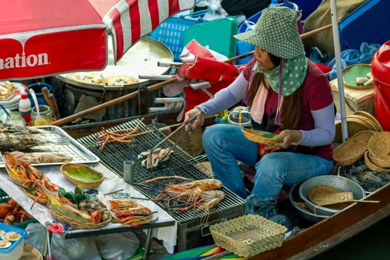intrepid-travel-thailand-bangkok-damnoen-saduak-floating-market-seafood-vendor-market-shutterstock-2420171545