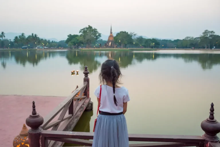 intrepid-travel-thailand-skuhothai-historical-park-evening-child-pond-stupa-distance-shutterstock-592621649